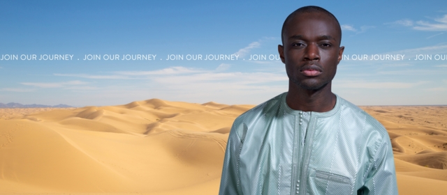 Man dressed in mint boubou in front of dunes